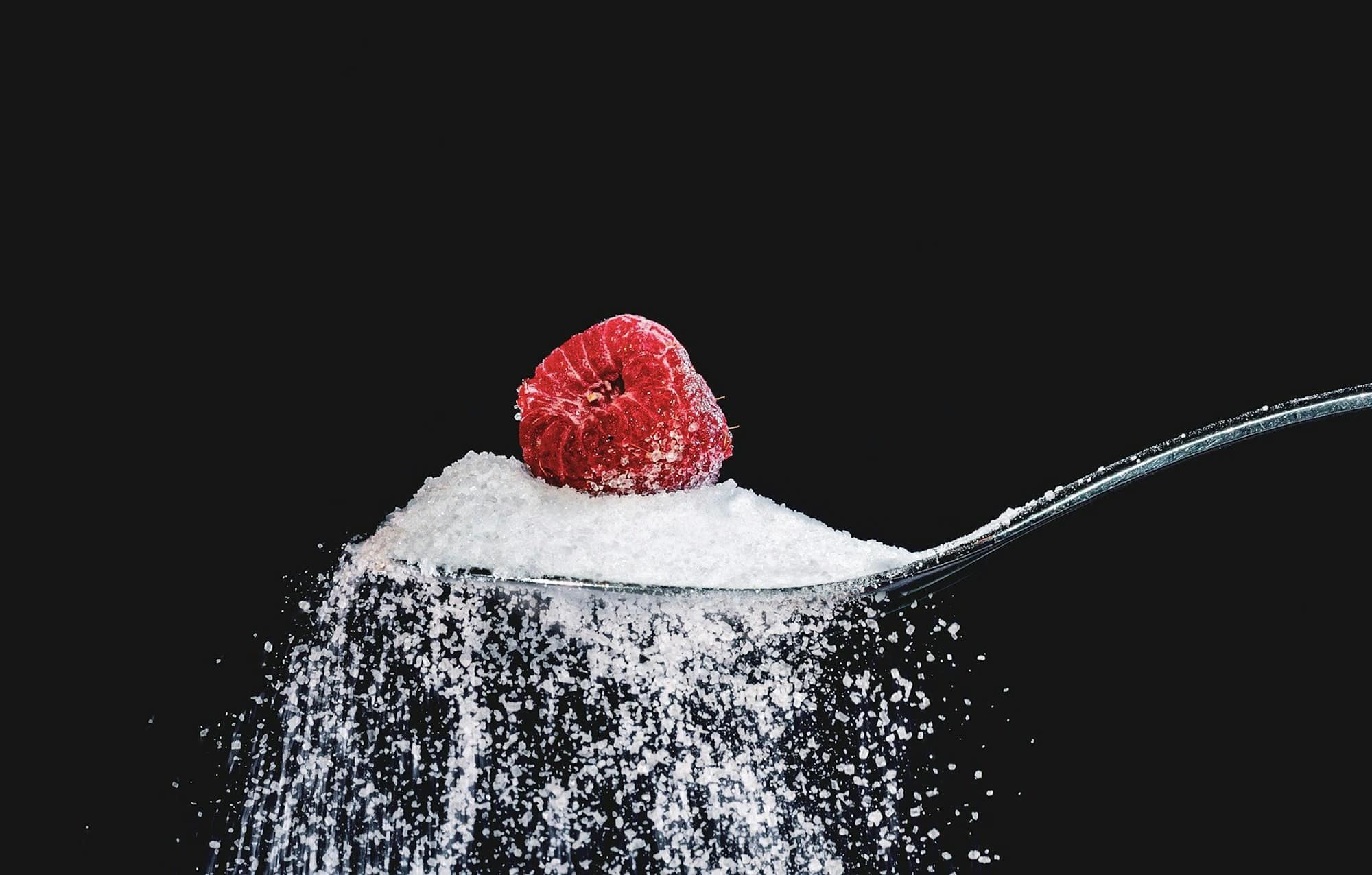 A spoonful of sugar with a raspberry on top of it.