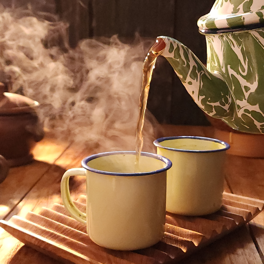 A hot tea pot pouring tea in a cup.