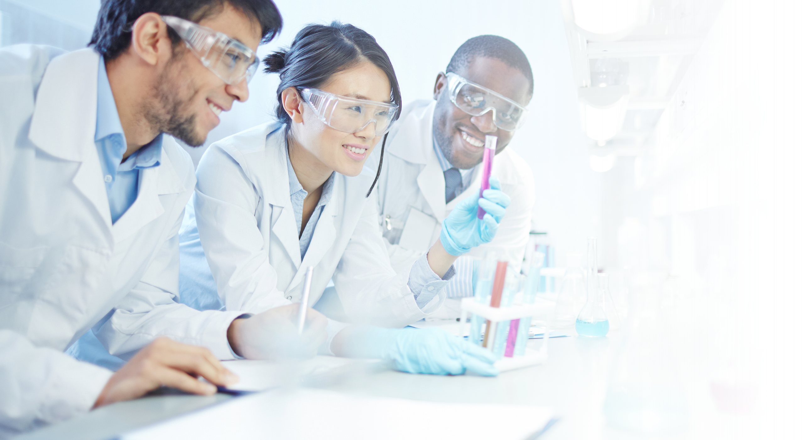 Three scientist in a laboratory holding a test tube.
